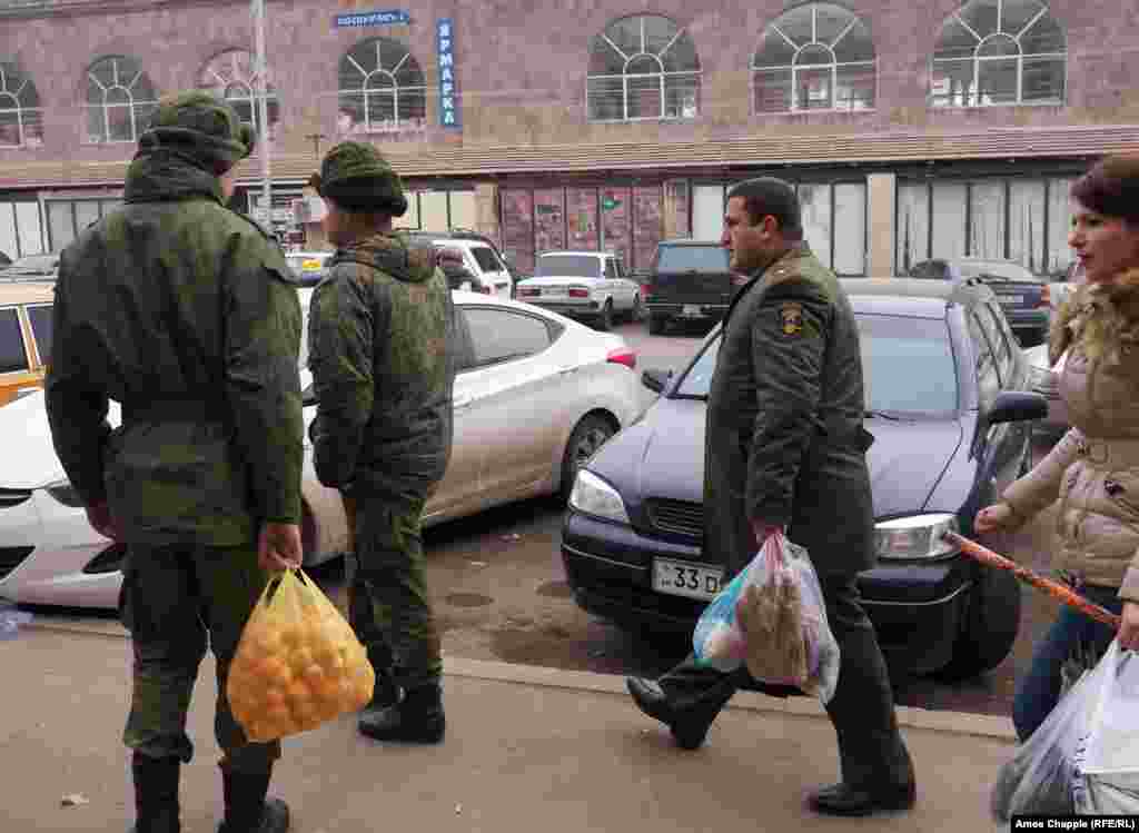 Офицер Вооруженных сил Армении проходит мимо российских военнослужащих на улице в Гюмри. Они видят друг друга, но не приветствуют