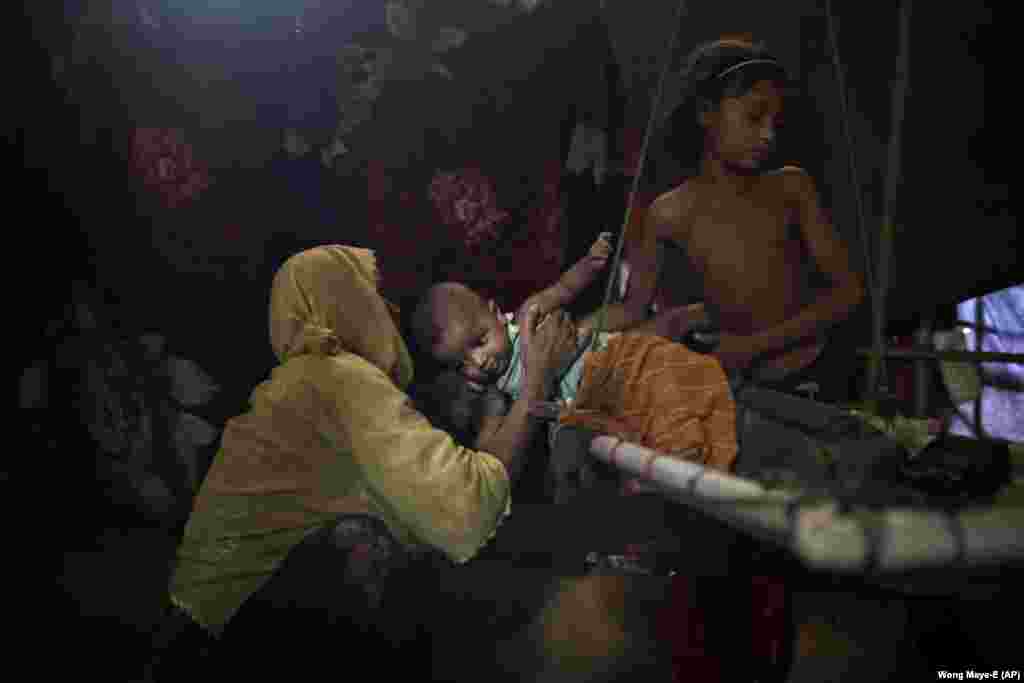 Девушка передает своего младшего брата в руки матери в лагере беженцев Кутупалонг в Бангладеш. По словам &quot;М&quot;, ее изнасиловали шесть солдатов армии Мьянмы, также они задушили ее двухлетнего сына.&nbsp;Позже женщина узнала, что беременна