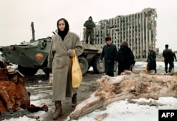 Жители Грозного проходят мимо танка российских федеральных войск и разрушенного здания президентского дворца Чечни. 1996 год
