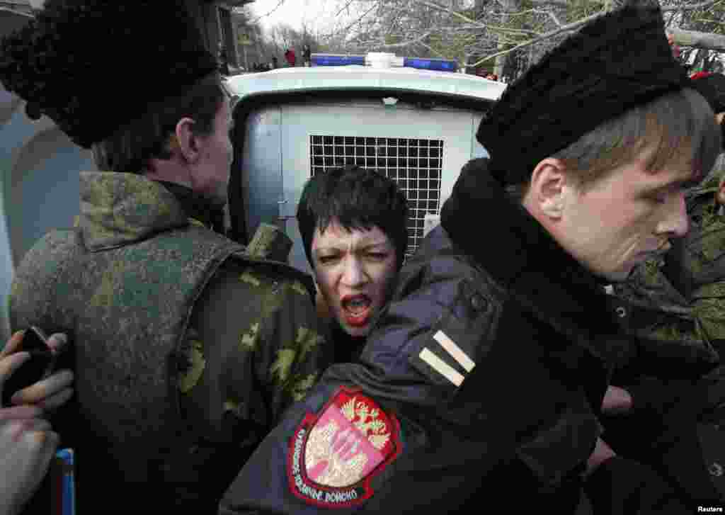 Члены самообороны блокировуют активистку движения Femen, которая принимает участие в антивоенной акции протеста возле здания крымского парламента в Симферополе, 6 марта 2014 года