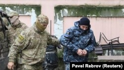 Сотрудник ФСБ ведет в суд одного из задержанных моряков