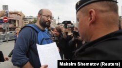 Полицейский зачитывает постановление муниципальному депутату Илье Азару