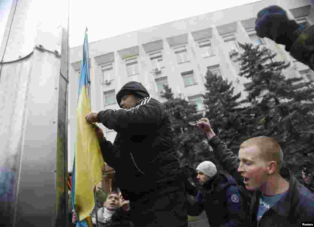 Пророссийские активисты снимают украинский флаг у горсовета Симферополя. 27 февраля 2014