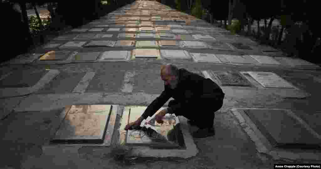 Мужчина моет плиты на крупнейшем тегеранском кладбище Бехеште-Захра. На нем также существует секция, посвященная падшим во время ирано-иракской войны. Раньше могилы там были окрашены в красный символизируя кровь мучеников