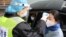 FILE PHOTO: A security officer in a protective mask checks the temperature of a passenger following the outbreak of a new coronavirus, at an expressway toll station on the eve of the Chinese Lunar New Year celebrations, in Xianning, a city bordering Wuhan