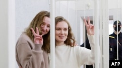 Belsat TV journalists Katsyaryna Andreyeva (r) and Daria Chultsova (l), who were detained in November 2020 while reporting on anti-government protests, flash the V-sign from a defendant's cage during their trial in Minsk on February 18, 2021.