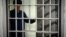 The guard looks into the prison cell