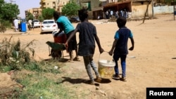 Дети в Хартуме идут за водой 22 апреля 2023 года. В столице Судана и других городах уже более недели продолжаются боевые столкновения. Фото: Reuters