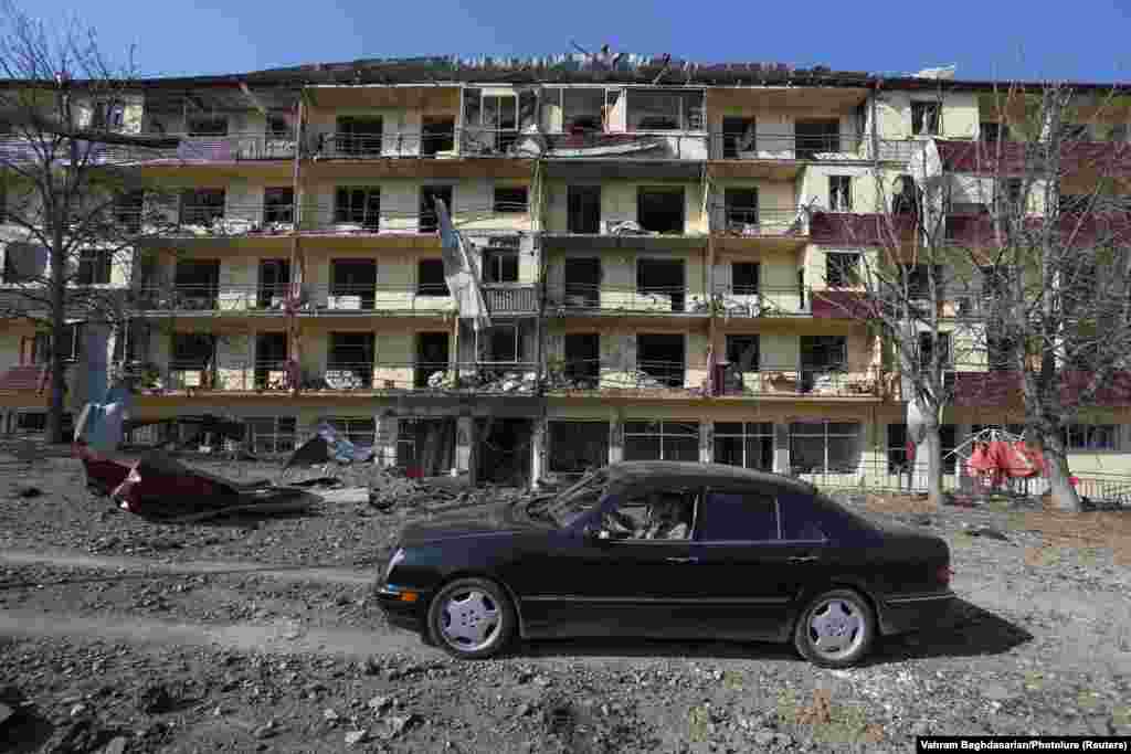 Before the arrival of Azerbaijani troops, a man drives a car past a building reportedly damaged from shelling of the Karabakhi town of Shushi (Shusha) in late October 2020.&nbsp; Badly damaged buildings from the first Karabakh war in the early 1990s can still be found throughout the town.