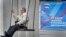 Russia -- A woman rides on a swing next to an election poster for the United Russia party ahead of the country's parliamentary elections to be held on September 18, in central Moscow, September 13, 2016