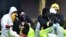 U.K. -- Members of the fire brigade are helped out of their green biohazard suits by colleagues in white protective coveralls after an operation to re-attach the tent over the bench where a man and a woman were found in critical condition sparking a major