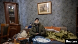 Житель Киева у себя дома в одежде из-за холода, вызванного отключением электричества и отопления после обстрелов армии РФ. 10 января 2026 года. Фото: Reuters