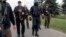 BELARUS -- This image made from video provided by the State TV and Radio Company of Belarus shows Belarus President Alyaksandr Lukashenka, second left, armed with a Kalashnikov-type rifle walks surrounded by his bodyguards near the Palace of Independence 