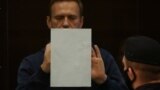 RUSSIA -- Russian opposition leader Alexei Navalny, accused of flouting the terms of a suspended sentence for embezzlement, writes inside a defendant dock during a court hearing in Moscow, Russia February 2, 2021.