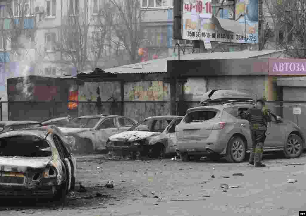 Военнослужащий украинской армии осматривает поврежденный автомобиль