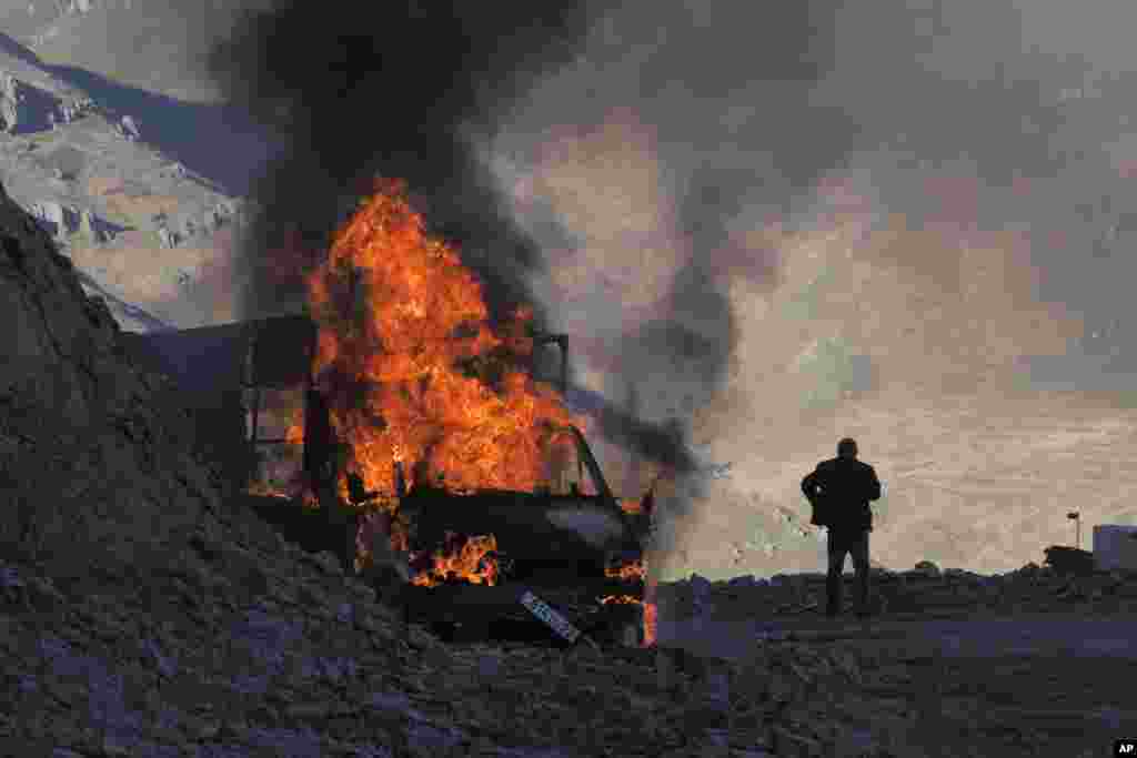 NAGORNO-KARABAKH - A man stands near his burning car which caught on fire during the climb along the road to a mountain pass, near the border between Nagorno-Karabakh and Armenia, Sunday, Nov. 8, 2020