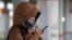 A commuter in a face mask uses a mobile phone at a station on the Moscow Central Circle
