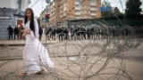BELARUS -- A woman walks past the barbed wire separating Belarusian servicemen and Belarusian opposition supporters during a rally in Minsk, August 30, 2020