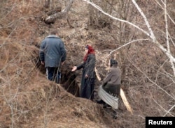Женщины из числа пензенских затворников и представитель администрации села Никольского Пензенской области возле входа в пещеру, 29 марта 2008 года. Восемь женщин к этому времени покинули "затвор", другие оставались под землей. Фото: Reuters