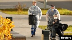 Medical workers push a woman in a wheelchair outside a hospital for patients infected with COVID-19 on the outskirts of Moscow on October 15, 2020. 