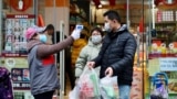 A worker measures body temperature of people leaving a supermarket in Qingshan district following an outbreak of the novel coronavirus in Wuhan, Hubei province, China February 7, 2020. Picture taken February 7, 2020. China Daily via REUTERS ATTENTION EDI