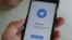 RUSSIA -- People pose with smartphones, with the Telegram logo seen on a screen - generic