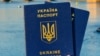 Generic – Woman's hand holding two Ukrainian passports in front of Prague old town cityscape