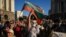 BULGARIA -- A man holds his fist in the air as another holds a Bulgarian flag during an anti-government protest in Sofia, July 29, 2020