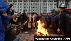 People protesting the preliminary results of a parliamentary vote in Bishkek gather by a bonfire in front of the seized main government building, known as the White House, on October 6, 2020.