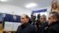 Italy -- Italian former premier and leader of Forza Italia (Go Italy) party Silvio Berlusconi, left, arrives at a polling station as a bare-breasted woman protests in background, in Milan, Italy, Sunday, March 4, 2018