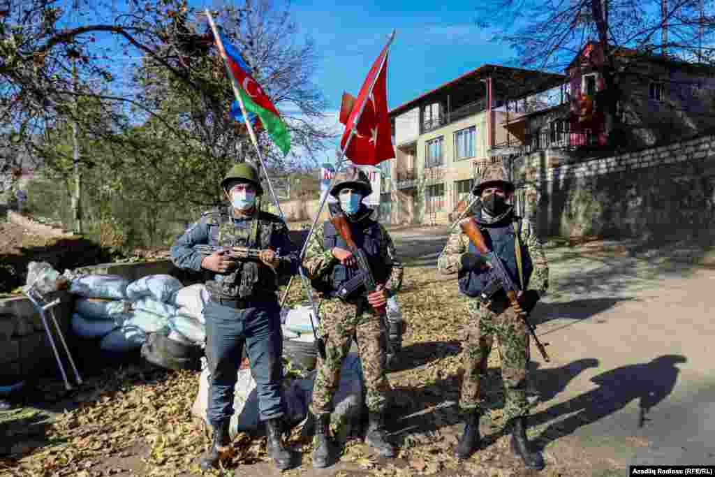 Azerbaijani servicemen stand guard before Azerbaijani and Turkish flags at a checkpoint in the Nagorno-Karabakh town of Hadrut on November 25, 2020. Azerbaijani prosecutors will investigate a video, widely distributed on social media, that allegedly showed Azerbaijani forces&#39; earlier execution of two ethnic Armenian men in Hadrut, Azerbaijani President Ilham Aliyev&#39;s senior foreign-policy aide Hikmat Hajiyev told PBS Newshour, a U.S. TV news program, on November 30, 2020.&nbsp;