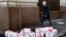 RUSSIA -- An opposition activist wearing a rubber mask depicting Russian President Vladimir Putin walks past gift boxes with letterings reading "trial", "resignation", "impeachment", "true election", "lustration" and others during an event dedicated to P