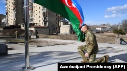 Azerbaijani President Ilham Aliyev kneels in front of the Azerbaijani flag during his visit to the Nagorno-Karabakh town of Shusha on January 15, 2021.