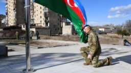 Azerbaijani President Ilham Aliyev kneels in front of the Azerbaijani flag during his visit to the Nagorno-Karabakh town of Shusha on January 15, 2021.