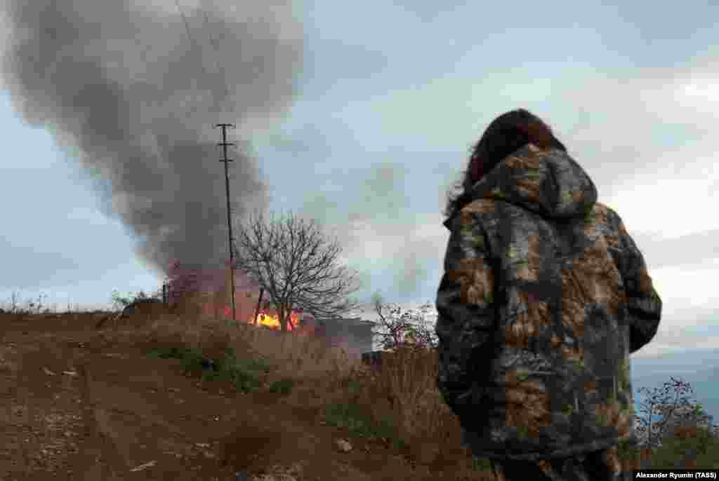 A local resident watches a burning house in the town of Lachin (Berdzor) on November 30, 2020, the day before the town returned to Azerbaijani control. Another town resident told Agence France Presse that he had no intention of leaving: &quot;People live on both sides of borders after wars, and things are fine,&quot; said the man, a grocery-store owner.&nbsp;