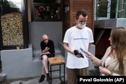A waiter on June 28, 2021 serves customers without QR codes outside of Moscow's usually crowded Moments bar.