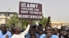 (FILES) Protesters react as a man holds up a sign demanding that soldiers from the United States Army leave Niger without negotiation during a demonstration in Niamey, on April 13, 2024.