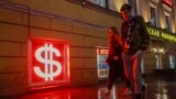 Young people walk past an illuminated US dollar sign