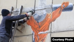 Рабочие "зачищают" граффити с распятым космонавтом в Перми 