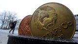 Belarus - A man walks past the giant Belarusian ruble coin monument near the Ministry of taxes-and-duties in Minsk. 22Feb2017