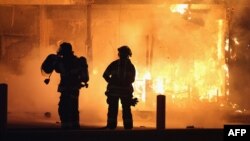 Пожарные пытаются потушить пожар в одном из подожженных зданий в Фергюсоне