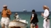 FILE PHOTO: Armed men stand on the beach as the Galaxy Leader commercial ship, seized by Yemen's Houthis last month, is anchored off the coast of al-Salif