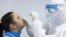 HUNGARY -- A medical student wearing protective clothing takes a swab sample for a COVID-19 rapid test in a school in Mandok, November 26, 2020