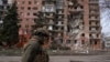 A Ukrainian serviceman passes by a residential building damaged by Russian military strikes in the frontline town of Pokrovsk