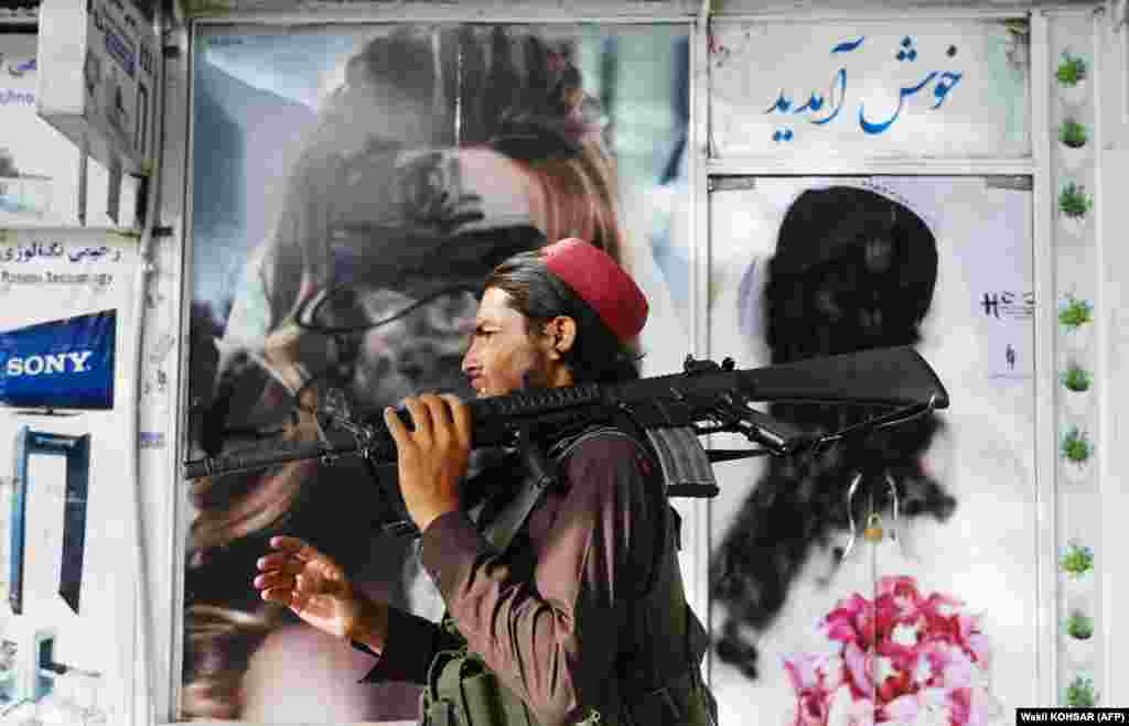 Член группировки &quot;Талибан&quot; проходит мимо рекламы салона красоты