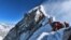 heavy traffic of mountain climbers lining up to stand at the summit of Mount Everest