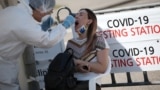KAZAKHSTAN -- A health worker takes a swab from a woman at a mobile testing station for the coronavirus disease (COVID-19) in Almaty, June 17, 2020