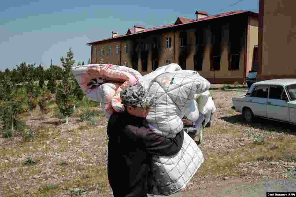 Житель села Максат переносит вещи после обстрелов. После начала конфликта на границе около 33 тысяч жителей приграничных территорий из обеих стран были эвакуированы