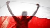 BELARUS -- Demonstrator is silhouetted by an old Belarusian national flag during a rally in Minsk, Belarus, Sunday, Oct. 4, 2020. 