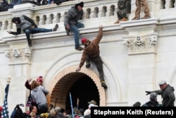 Pro-Trump protesters scale a wall as they storm the U.S. Capitol building during clashes with Capitol police at a January 6, 2021 gathering to contest Congress' certification of the 2020 U.S. presidential election results.